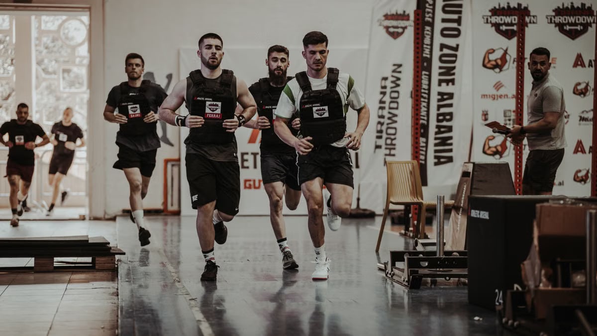 Group of men running in an indoor fitness competition, showcasing athleticism and determination.